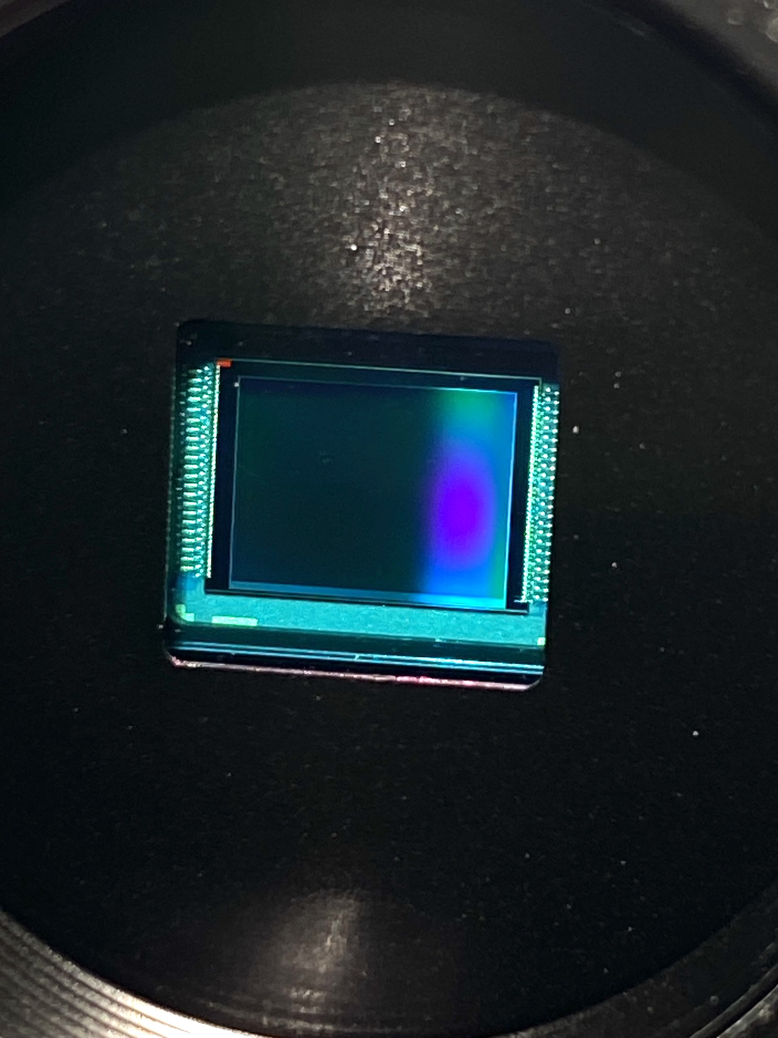 Gros plan du capteur Sony IMX477 de PiNox, sans objectif, avec des reflets colorés sur sa surface.